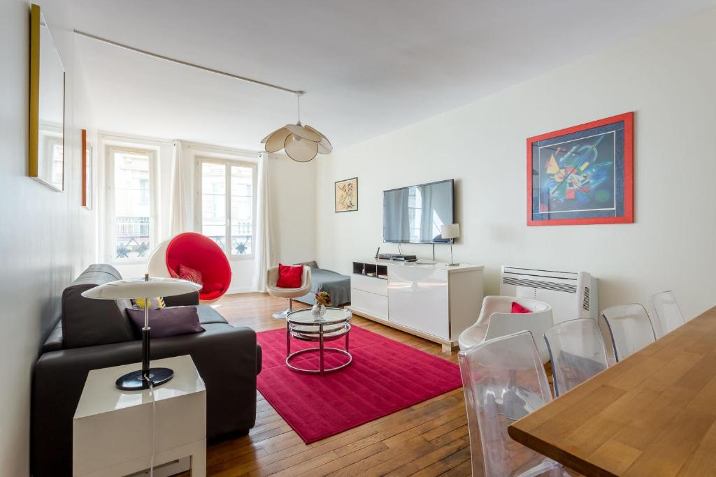 a living room with a black couch and a red rug at Saint Honore Louvre in Paris