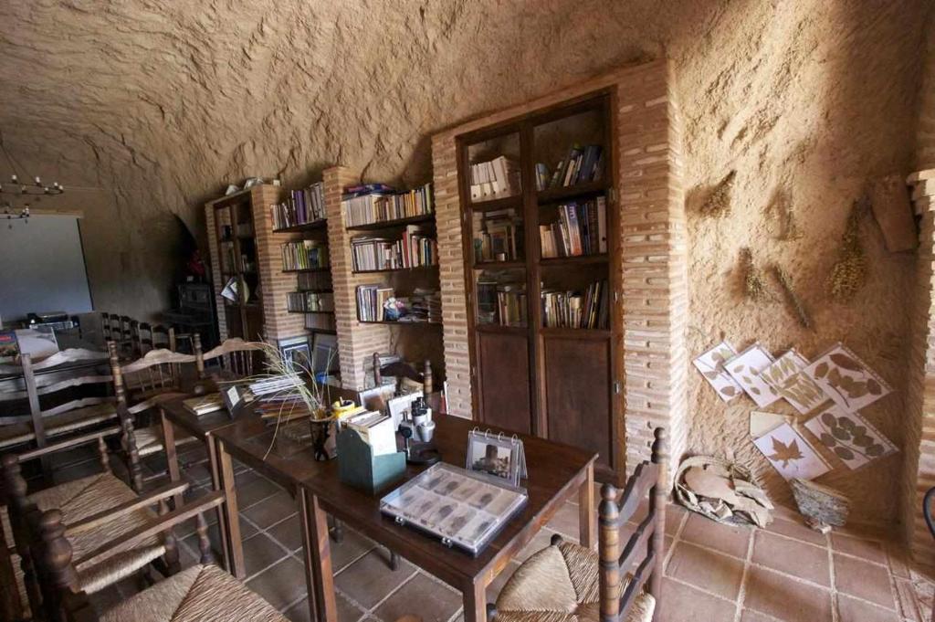 Habitación con mesa y estanterías en Hábitat Troglodita Almagruz, en Purullena