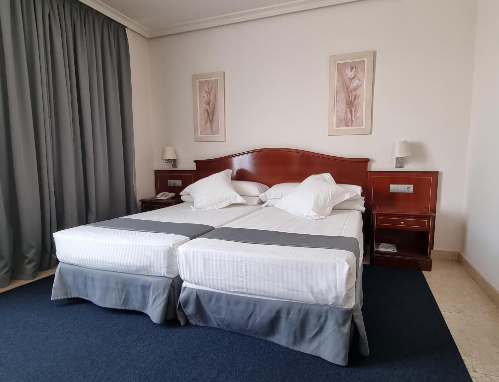 a bedroom with a large bed with white sheets at Hotel Gran Legazpi in Madrid