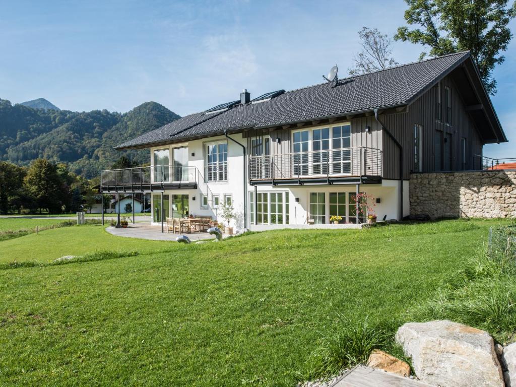 una casa con un gran césped delante de ella en Ferienwohnungen am Lochbach en Aschau im Chiemgau