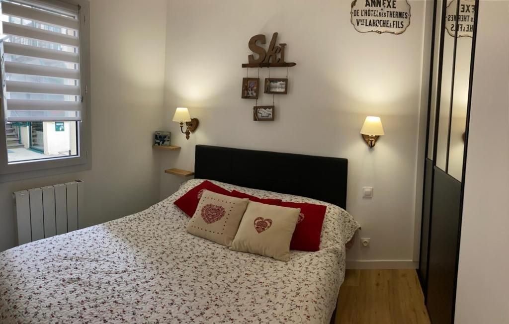 a bedroom with a bed with red pillows and a window at Appartement Les Amethystes 1 in Le Mont-Dore