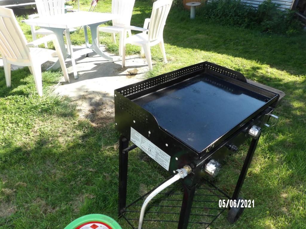 a grill in the grass with a table and chairs at Calme de la campagne in Le Torp-Mesnil