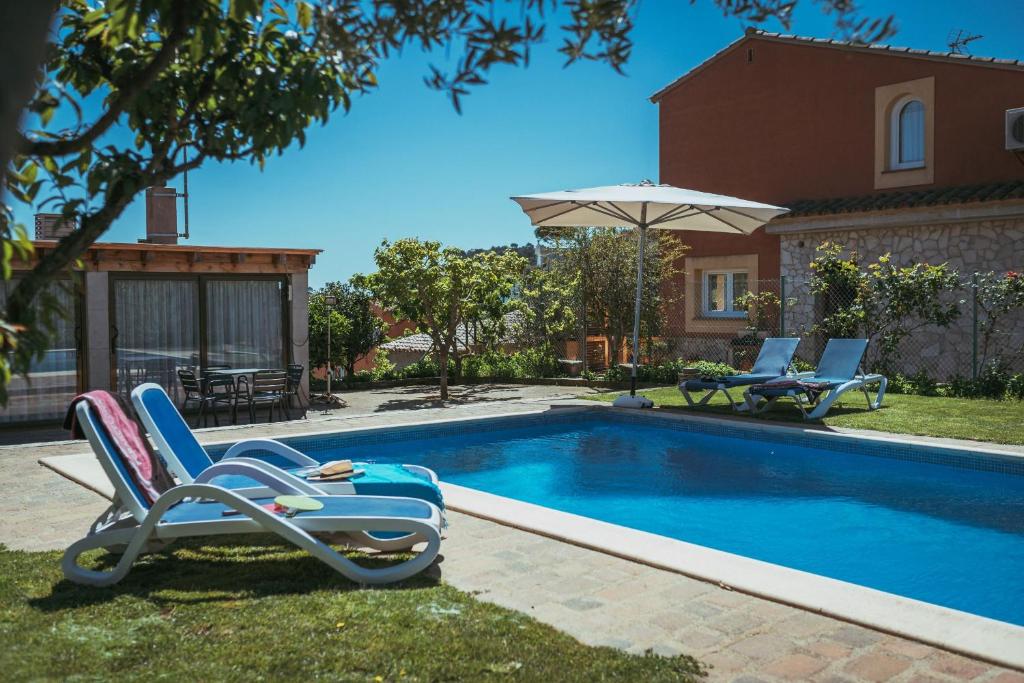 een zwembad met 2 ligstoelen en een parasol bij Casa Adela in Begur