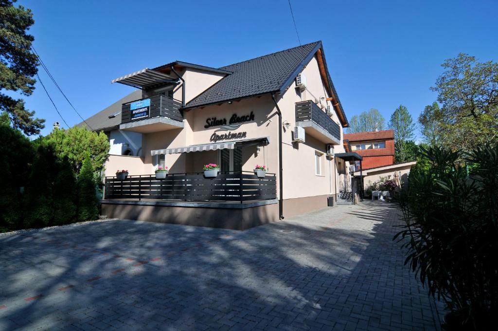 ein weißes Gebäude mit einer Veranda und einem Gehweg in der Unterkunft Silver Beach Apartments in Siófok