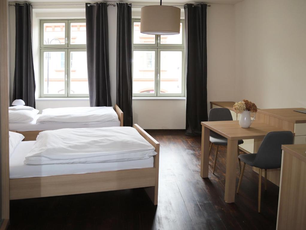 a room with two beds and a table and chairs at Rezidence U Kamenného mostu in Písek