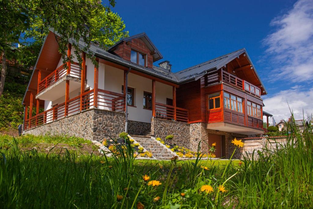 duży drewniany dom z trawnikiem przed nim w obiekcie Domek nad Kryniczanką w mieście Krynica Zdrój