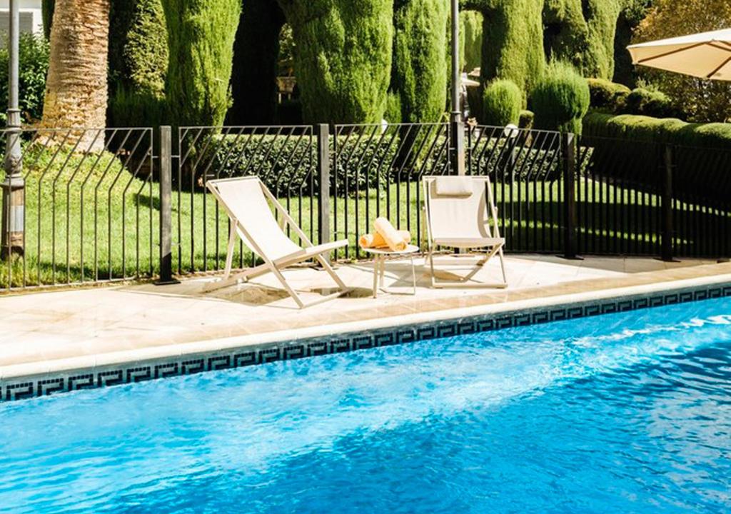 two chairs and an umbrella next to a swimming pool at Parador de Mérida in Mérida
