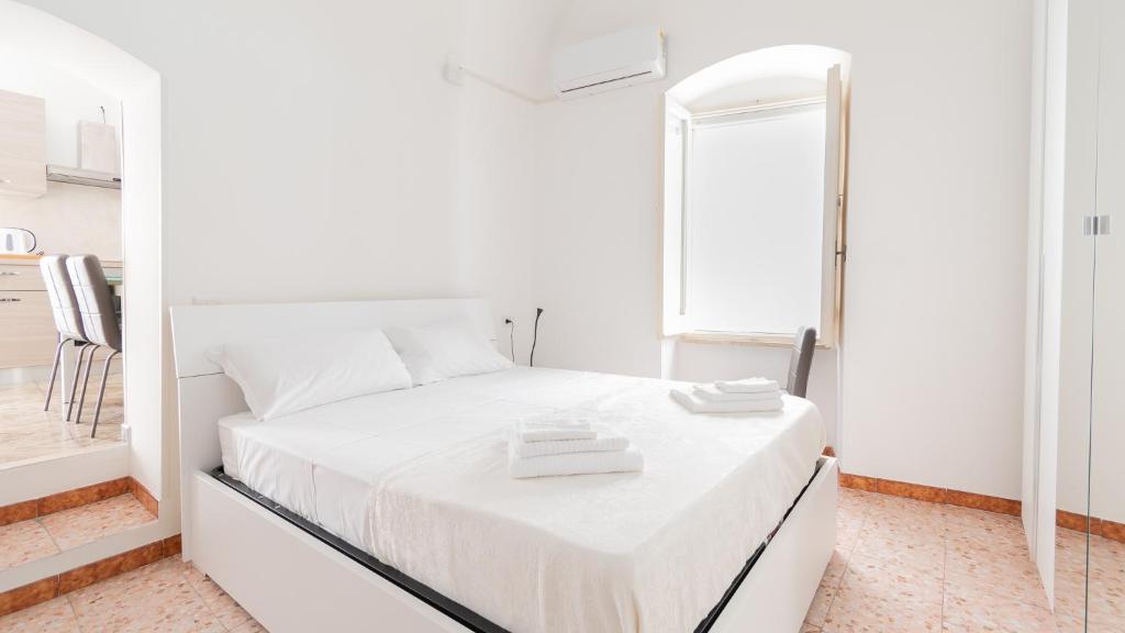 ein weißes Schlafzimmer mit einem weißen Bett und einem Spiegel in der Unterkunft Alloggio da Paolina in Castellaneta