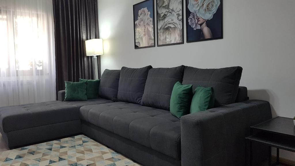 sala de estar con sofá gris y almohadas verdes en Mary Apartment en Galaţi