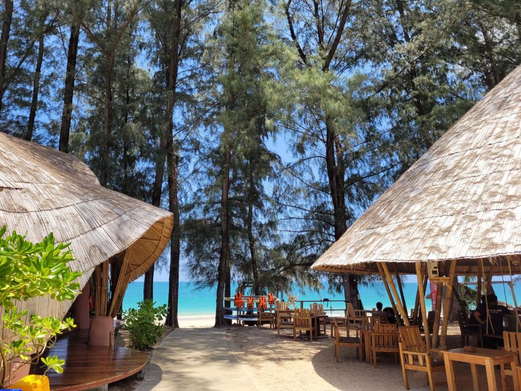 
a beach area with tables, chairs and umbrellas at Long Beach Chalet - SHA Extra Plus in Ko Lanta
