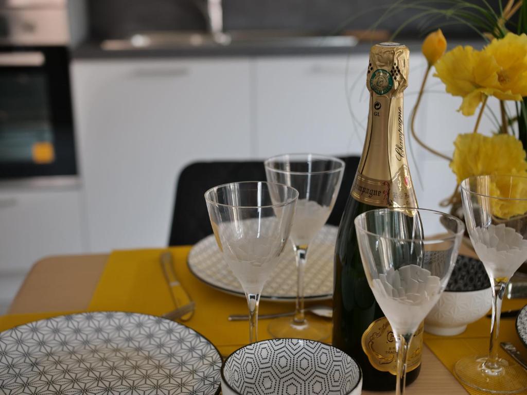 Una botella de champán sentada en una mesa con copas de vino en Plage à 50m Appartement Rêves étoilés Villa Les Bains de Mers, en Mers-les-Bains