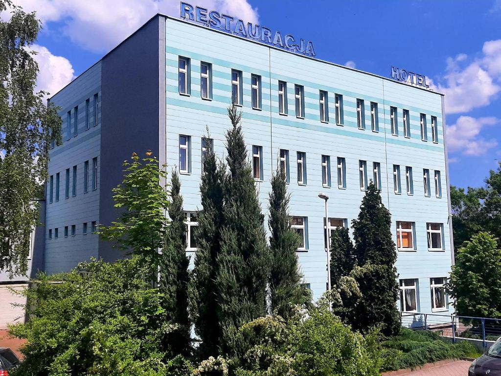 a white building with a sign on the top of it at Hotel Marco in Będzin