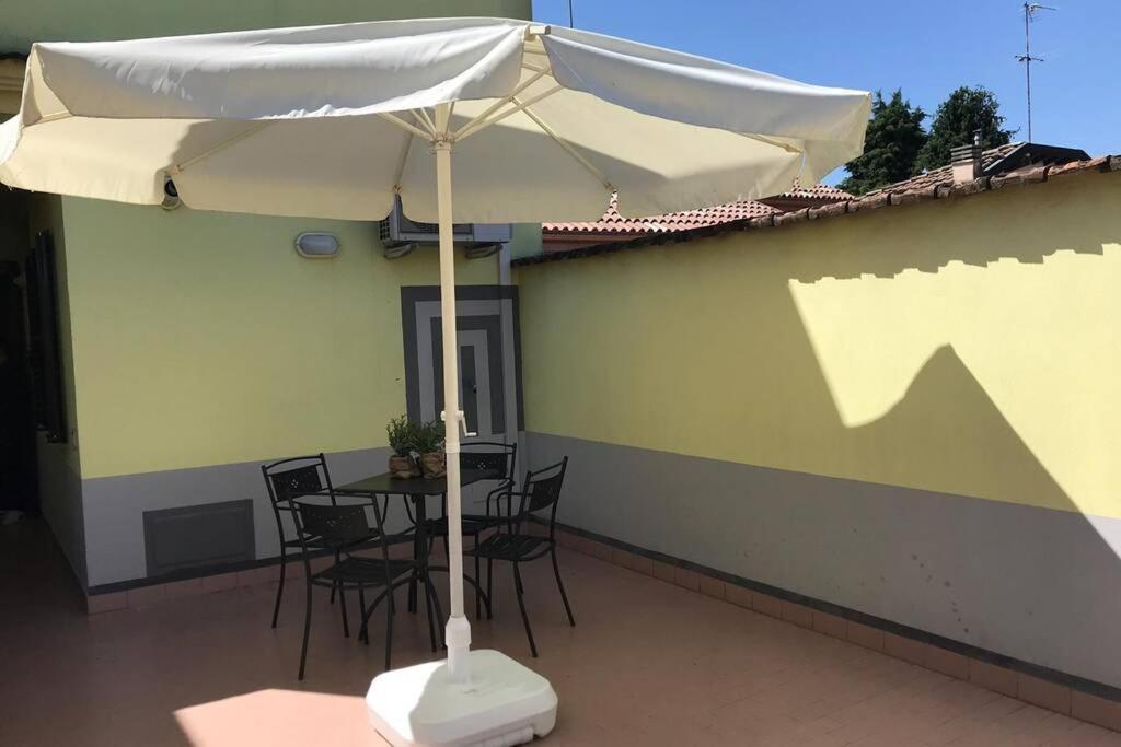ein weißer Regenschirm auf einer Terrasse mit Stühlen und einem Tisch in der Unterkunft Aperitivo in terrazza vicinissimo al centro. in Parma