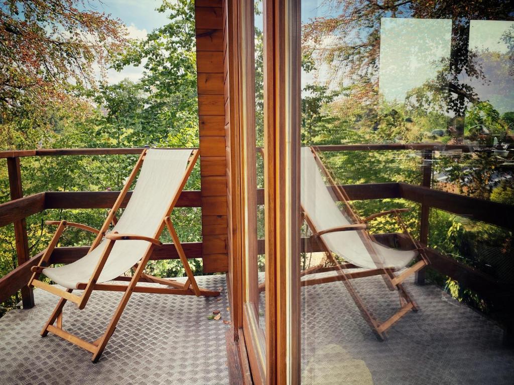 un fauteuil à bascule assis sur une terrasse couverte avec une fenêtre dans l'établissement Nîdwazô - Ecolodge & Maison d'hôtes, à Trooz