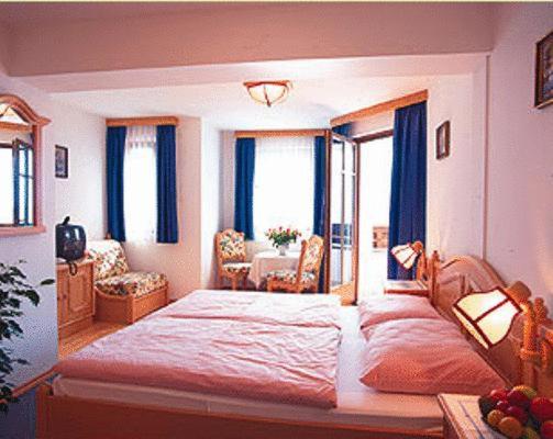 a bedroom with a large bed with blue curtains at Pension Linortner in St. Wolfgang