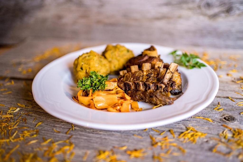 a plate of food with meat and potatoes on a table at Tourist Farm Šenkova Domačija in Zgornje Jezersko