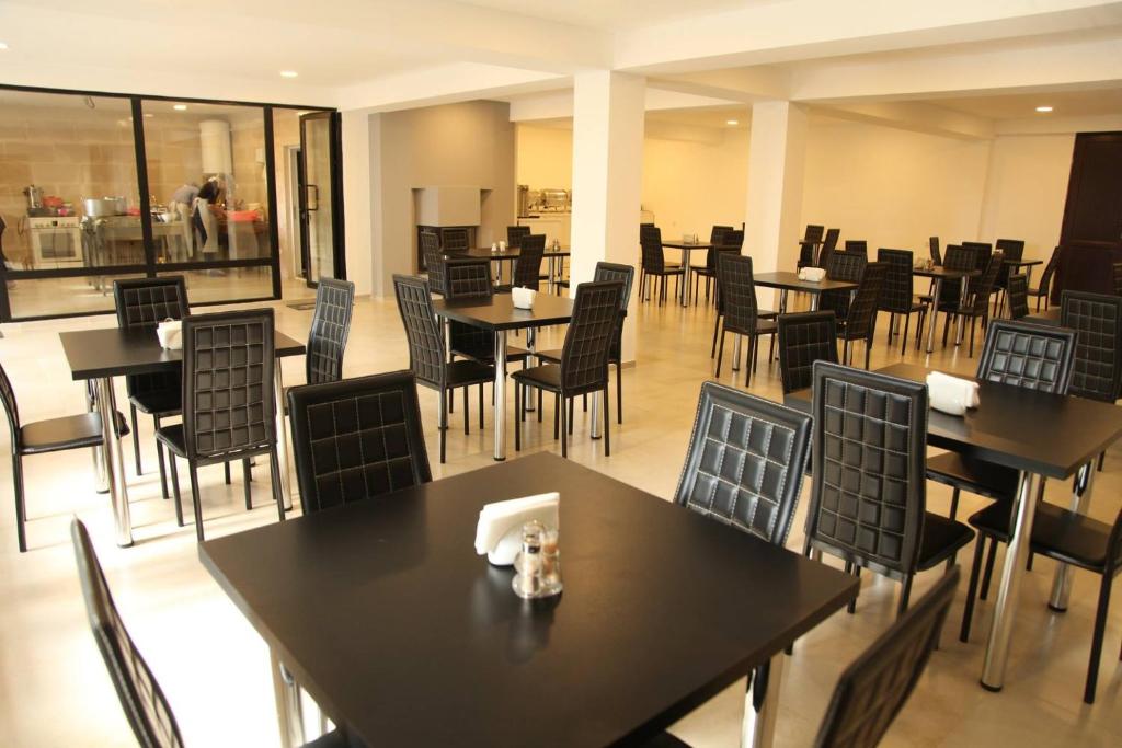 un ristorante con tavoli e sedie neri e cercatore di tavoli di Hotel Chubu a Mestia