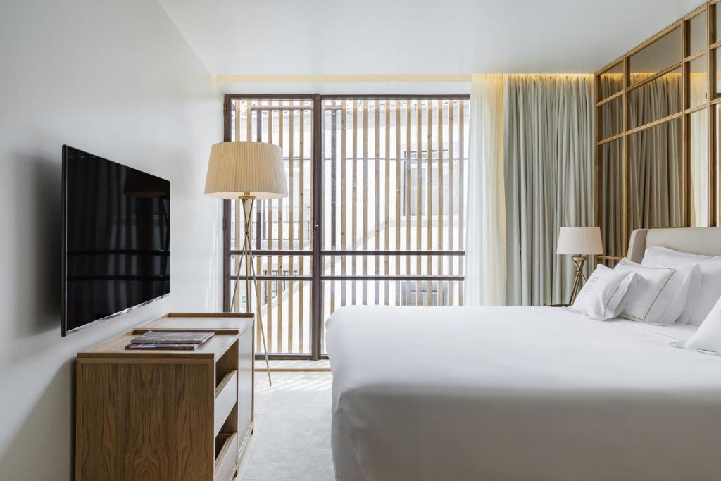 a bedroom with a large white bed and a television at Casa da Companhia, Vignette Collection by IHG in Porto