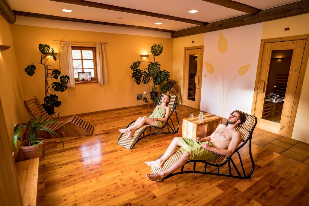 two people sitting in chairs in a living room at Tourist Farm Šenkova Domačija in Zgornje Jezersko
