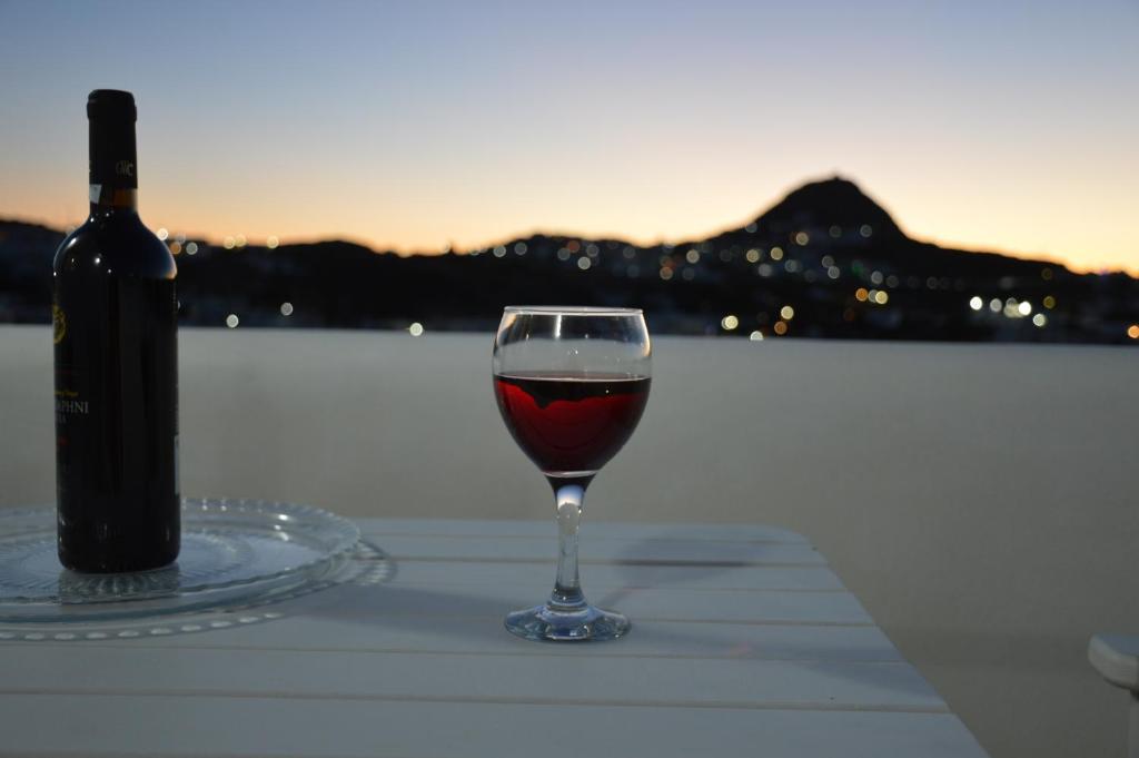 ein Glas Wein auf einem Tisch mit einer Flasche Wein in der Unterkunft Rhyolite Apartment in Triovasálos