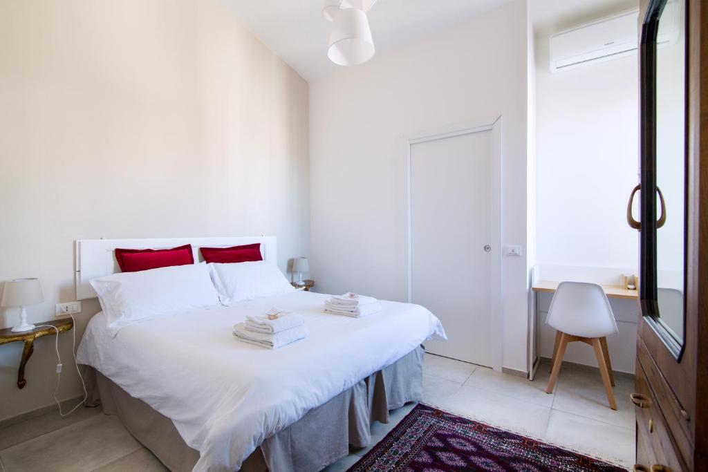a white bedroom with a large white bed with red pillows at Dei Molini in Foligno