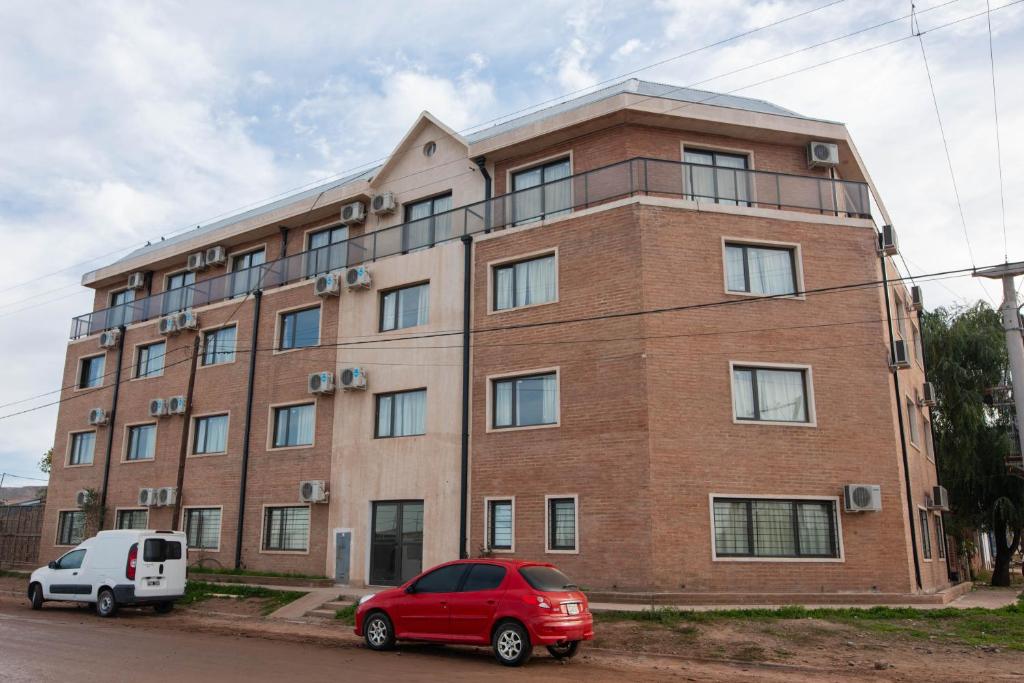 a brick building with a red car parked in front of it at Edificio Pampa II in Añelo