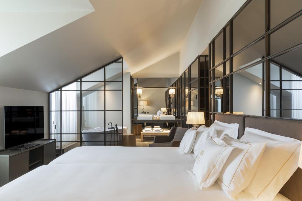 a bedroom with a large white bed and a bathroom at Casa da Companhia, Vignette Collection by IHG in Porto