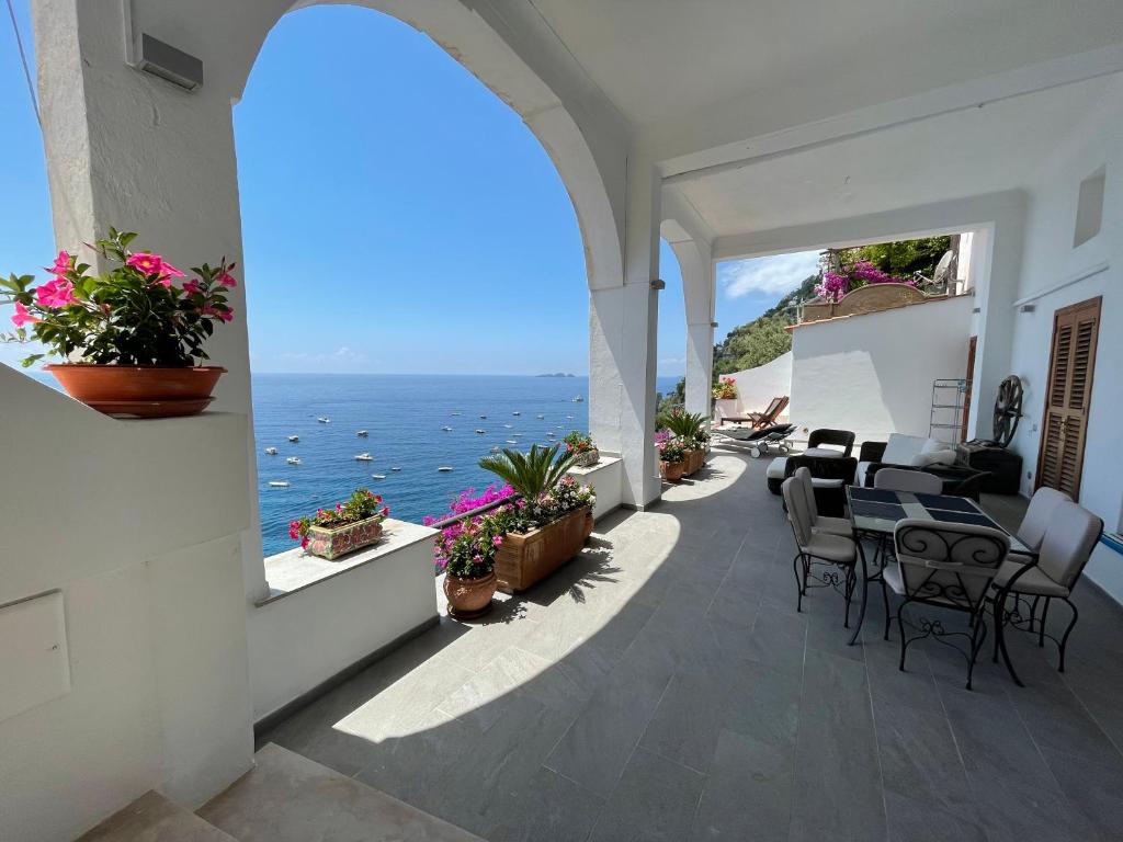 Un patio con mesa y sillas y el mar. en Casa Antioco Original, en Positano