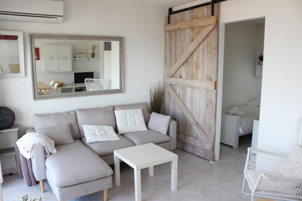 a living room with a couch and a sliding barn door at Beautiful apartment in front of beach, pool, view in Roses