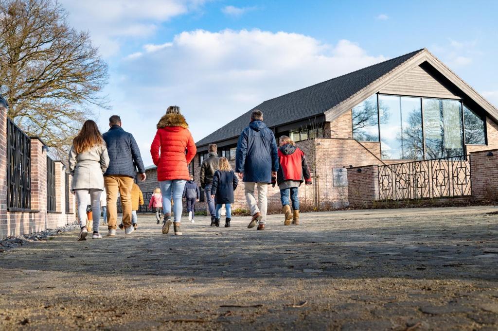 un grupo de personas caminando por una acera frente a una iglesia en De Zwaluwhoeve, en Peer