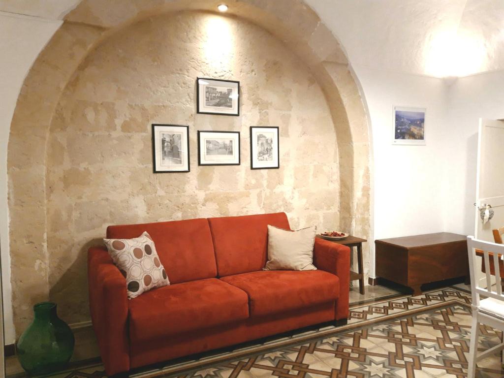 マテーラにあるL'eco dei sassiの石壁のリビングルーム(赤いソファ付)