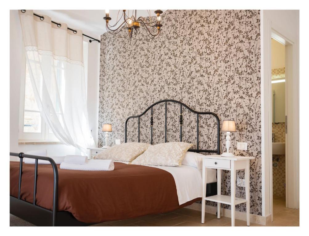 1 dormitorio con cama y pared con papel pintado con motivos florales en RESIDENCE IL GROTTINO, en Gualdo Cattaneo