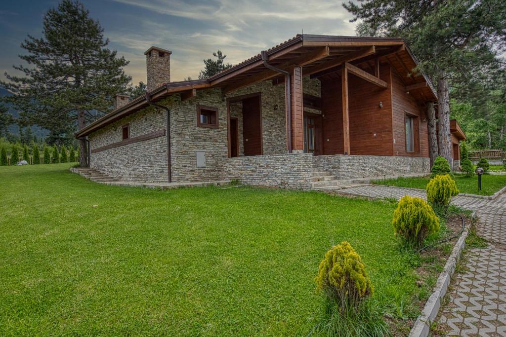 uma grande casa de pedra com um jardim de relva em Pirin Style Villa & Spa em Bansko