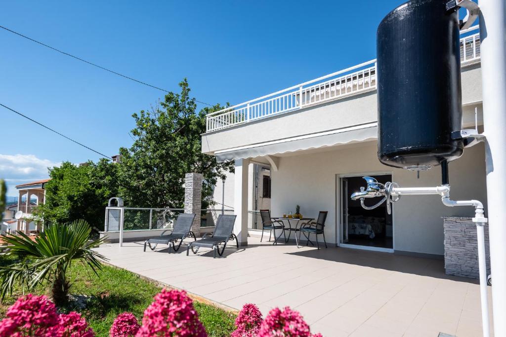 Cette maison dispose d'une terrasse avec des chaises et une table. dans l'établissement Apartments Omorfia, à Kraljevica