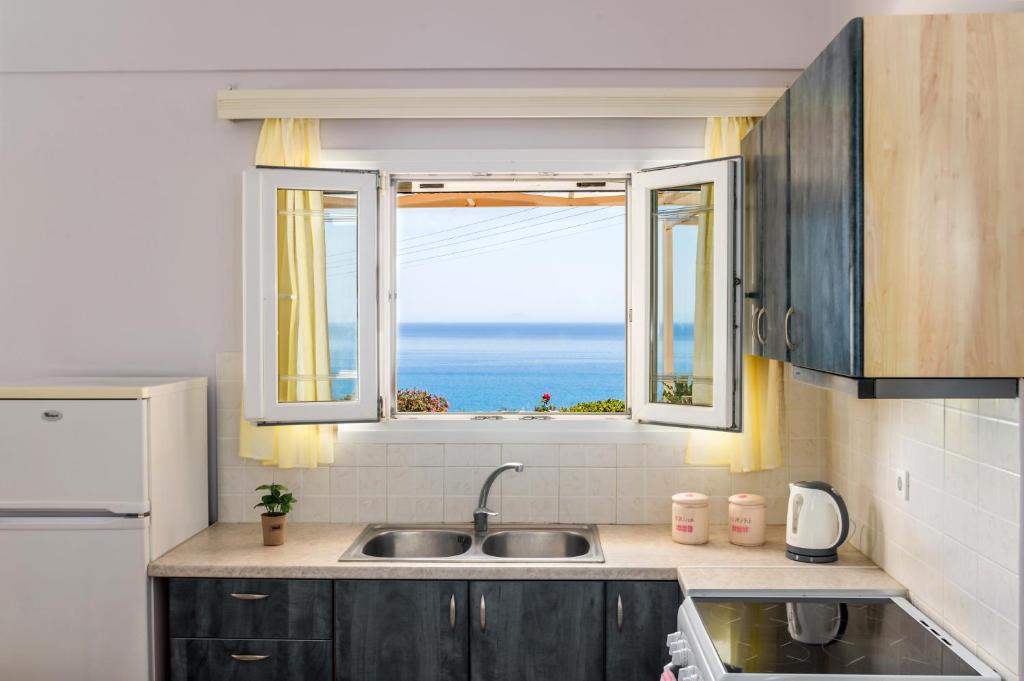 a kitchen with a sink and a window with the ocean at Asta La Vista Maisonettes in Pesádha