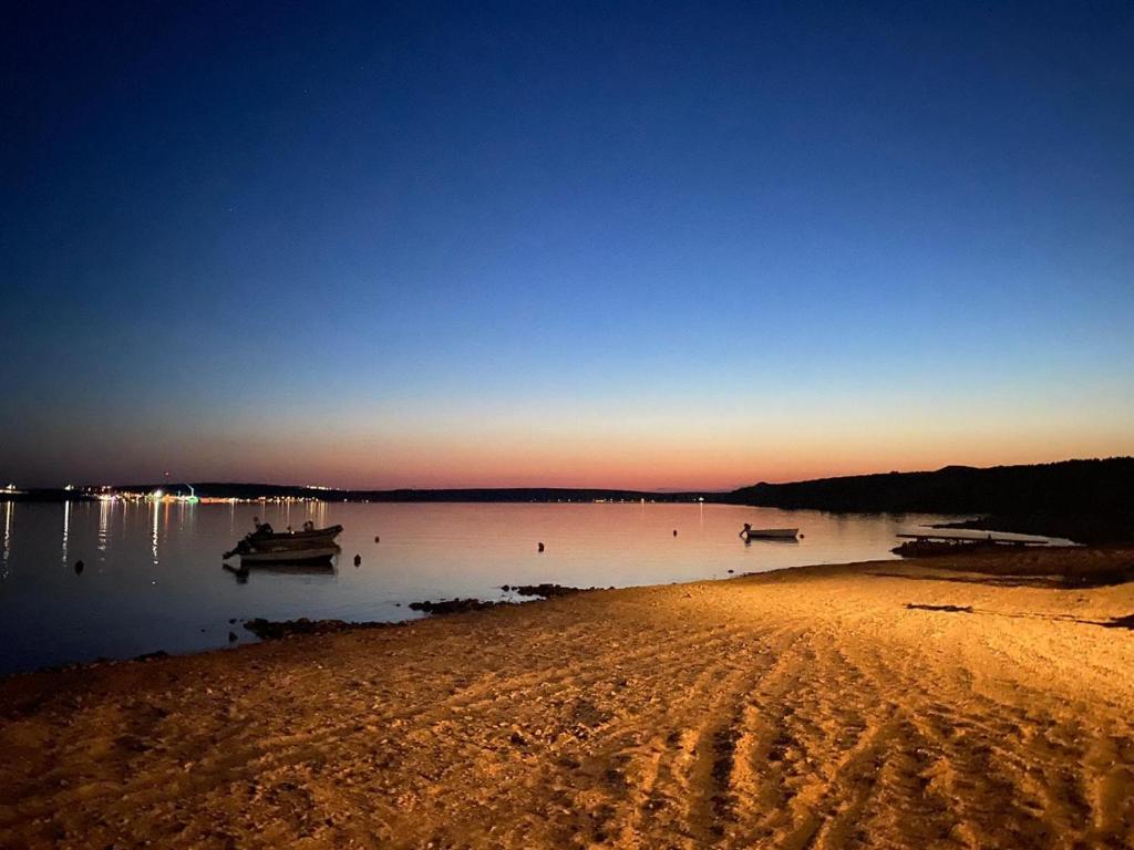 a beach with boats in the water at sunset at Apartments Ivana in Zubovići