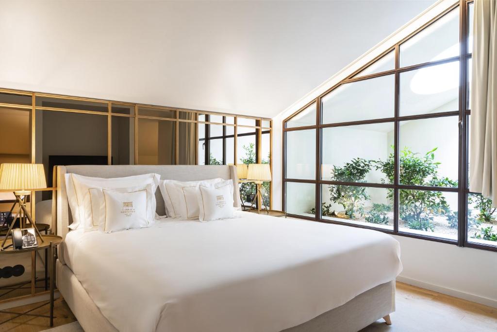 a bedroom with a large white bed with windows at Casa da Companhia, Vignette Collection by IHG in Porto