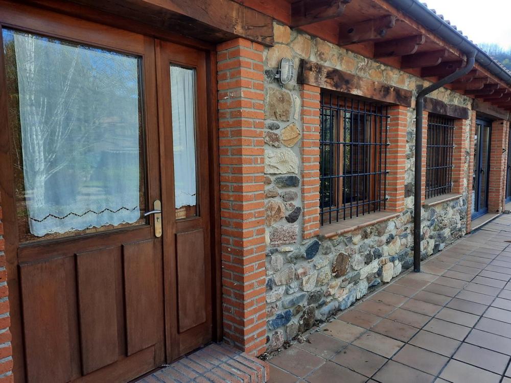 un edificio de ladrillo con puertas y ventanas de madera en LOFT ROBLE - Chousa Verde, en Vegacervera