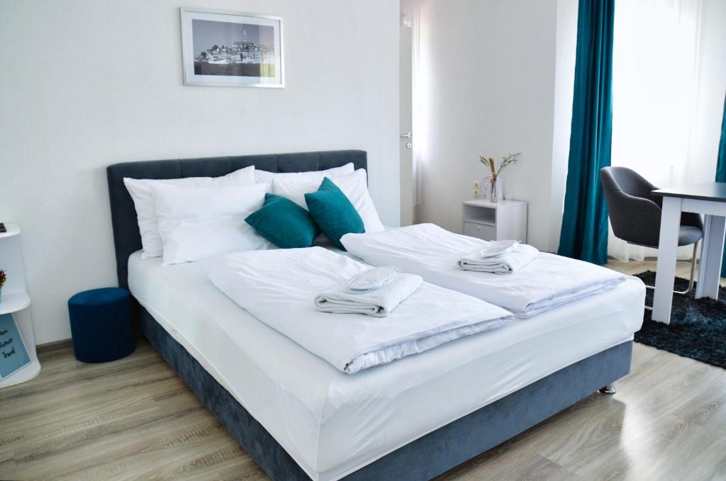 a bedroom with a bed with white sheets and blue pillows at Guesthouse Marivo in Jajce