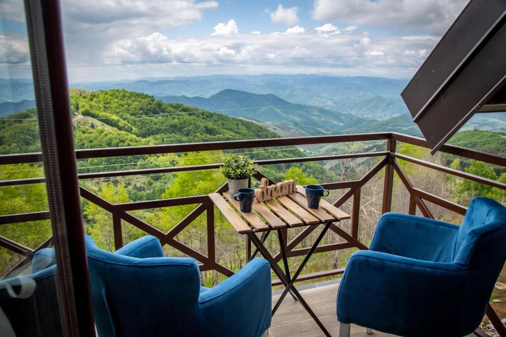 een tafel en stoelen op een balkon met uitzicht op de bergen bij Apartments View Dvori E25 in Kopaonik