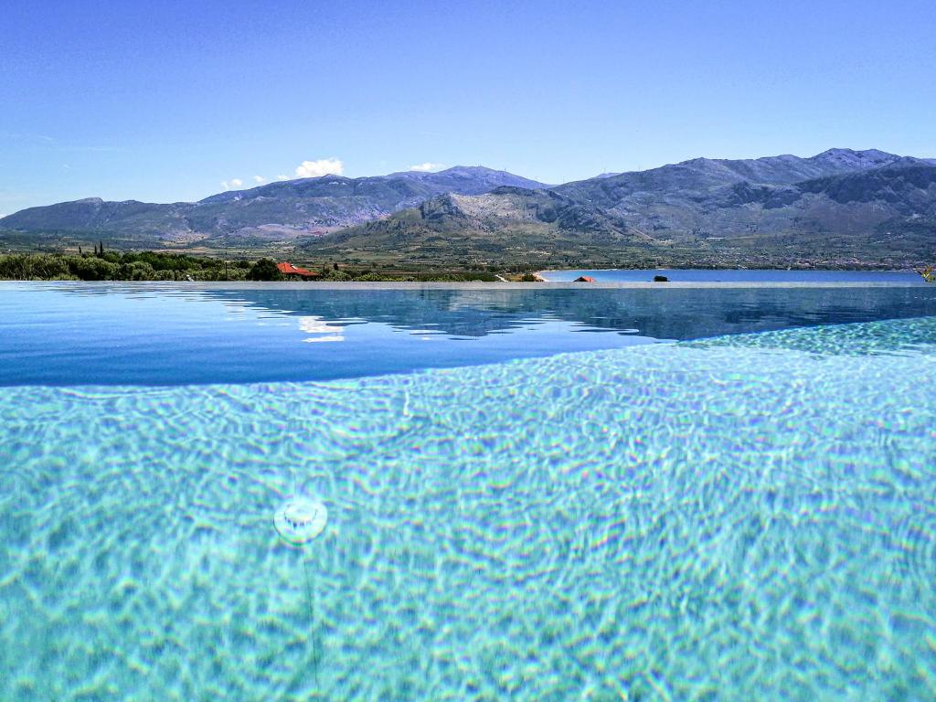 a pool of blue water with mountains in the background at Villa Helena in Paleros