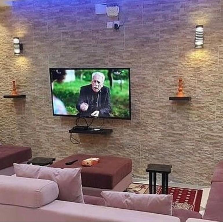 a living room with a tv on a brick wall at شاليهات شاطئ ارينا in Qarār