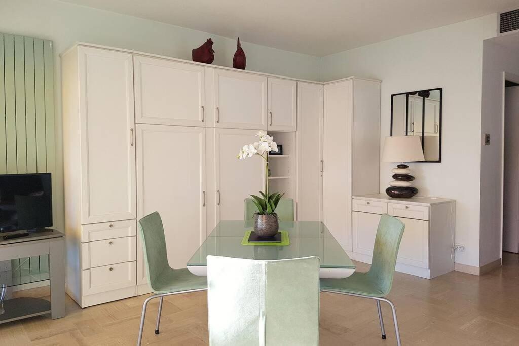 une salle à manger avec une table en verre et des chaises vertes dans l'établissement C045-Lovely apartment - private residence over the sea, à Cannes