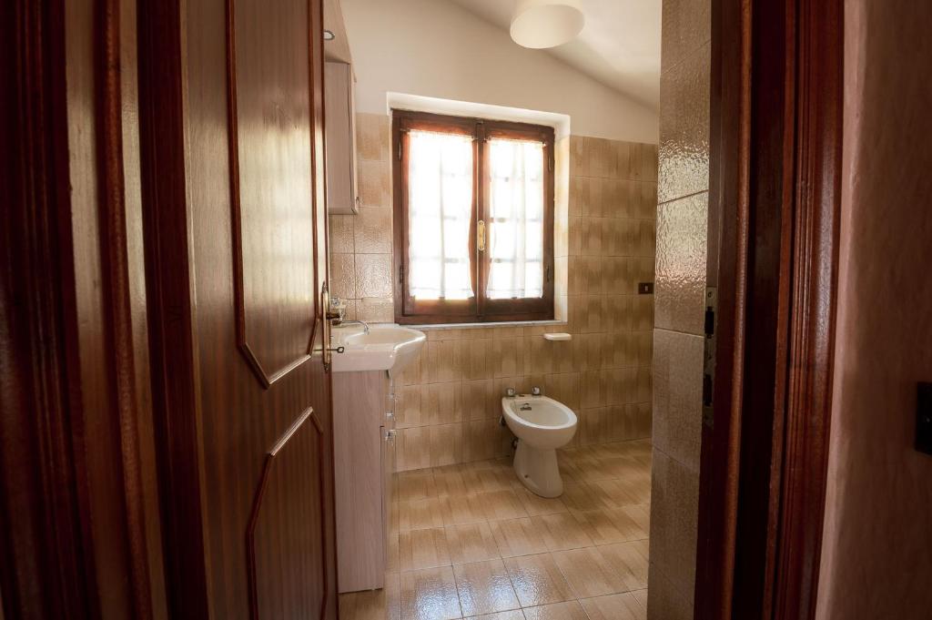 a bathroom with a toilet and a sink and a window at Casa Vacanze Dante in Gorfigliano