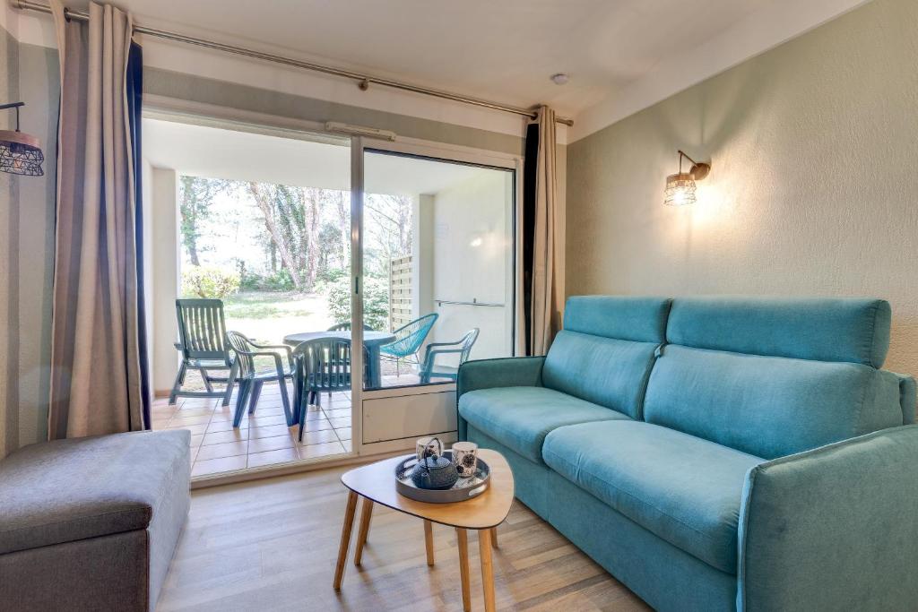 un salon avec un canapé bleu et une table dans l'établissement Le Zeste, à Soustons