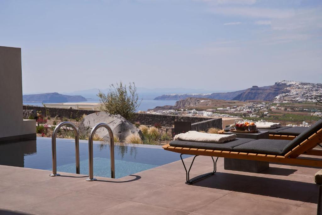 a pool with a table and a bench next to a pool at Apikia Santorini in Pirgos