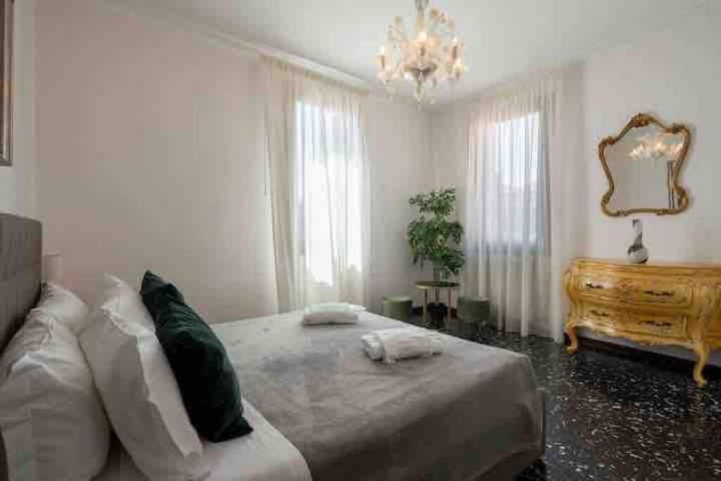 a bedroom with a large bed and a chandelier at Ca’ Pesaro rooftop terrace apartment. in Venice