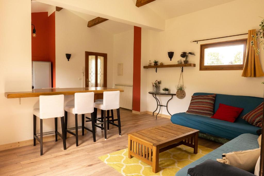 uma sala de estar com um sofá azul e uma cozinha em Gites de la Lurette - T3 lumineux et spacieux dans cadre calme et verdoyant em Cazilhac