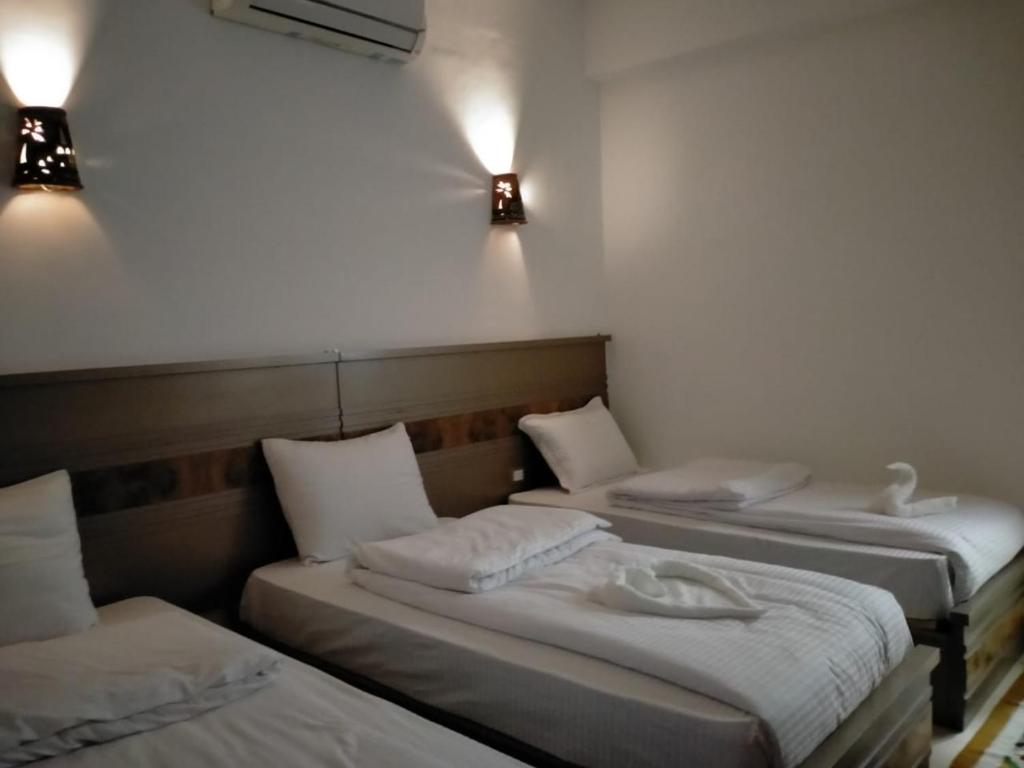 three beds in a room with lights on the wall at Villa 22 in Dahab