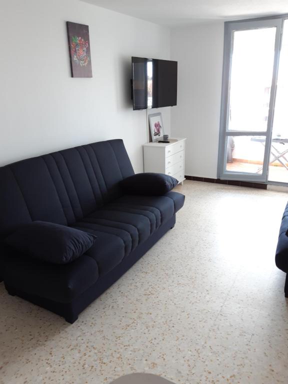- un canapé noir dans le salon doté d'une télévision dans l'établissement Studio plage du môle, au Cap d'Agde